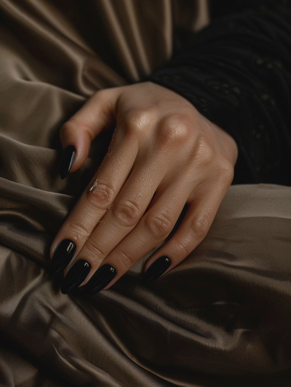 Create a photorealistic image capturing sophisticated and bold black nails, rendered in exquisite detail, evoking a snapshot from real life. The nails, painted with a glossy, jet-black polish, should gleam under the soft glow of natural light, highlighting the subtle imperfections of real nails—tiny ridges and the minute variance in cuticle shape. Use a camera setting that mimics a full-frame DSLR, with a 50mm prime lens at f/1.8 to achieve a shallow depth of field, focusing sharply on the nails against a softly blurred background. The lighting should utilize global illumination techniques, simulating mid-afternoon sunlight filtered through a sheer curtain, creating a balance of light and shadow that accentuates the nails' boldness and the texture of the skin. Reference high-quality 2020s visual content for style, aiming for the naturalistic yet aspirational aesthetic found in the work of photographers like Jamie Nelson or the atmospheric, intimate scenes of a Luca Guadagnino film. The composition should be balanced, with the hands positioned gently on the lap of the subject, wearing a fabric with a subtle, luxurious texture to complement and not compete with the nails' statement. Aim for sharp focus, high detail, and a touch of film grain to add texture and depth, instilling the image with a sense of tangible reality.